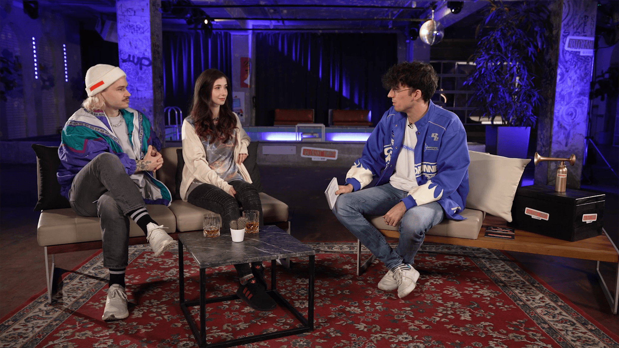 Die G&auml;ste der Show Vlesk und Basos sitzen auf dem Sofa neben Mango. Show guests Vlesk and Baso are being introduced by host Mango while sitting on a sofa.