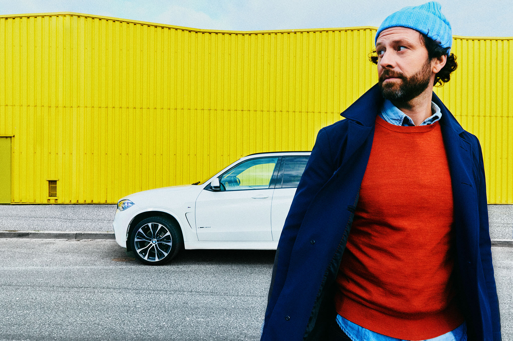 Mann mit M&uuml;tze, im Hintergrund Auto und gelbes Geb&auml;ude / Man with cap, car and yellow building in background